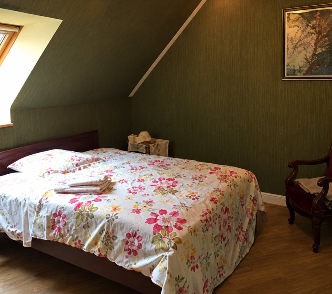 Chambre mansardée avec un lit et son couvre-lit fleuri
