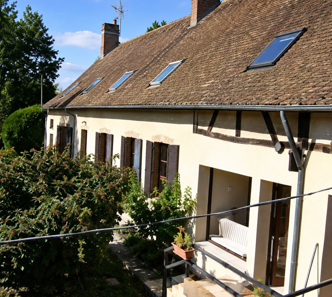 Maison ancienne au toit de tuiles avec fenêtres de toit, côté jardin